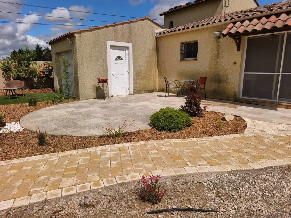 Après : jardin aménagé avec allée pavée et massifs devant la maison