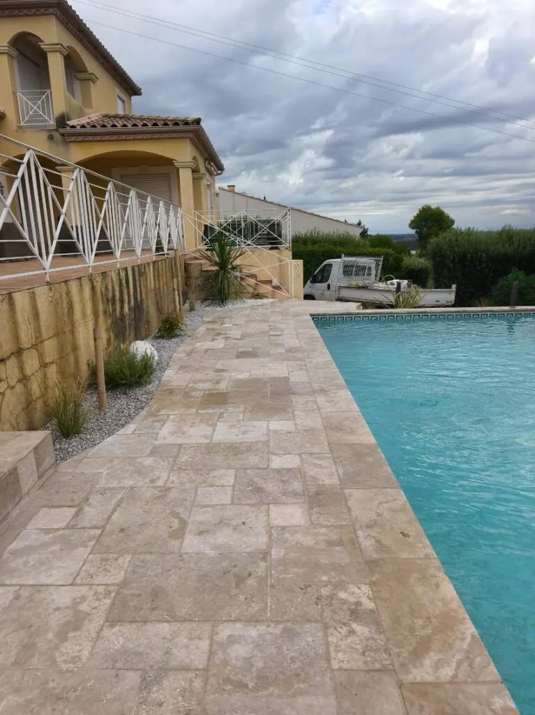 Plage de piscine en pierre le long d'une maison