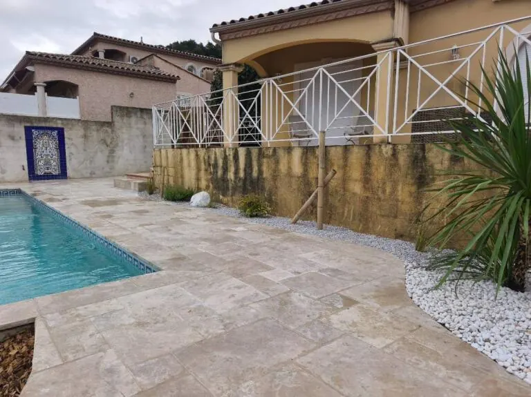 Plage de piscine en pierre avec massif de galets blancs