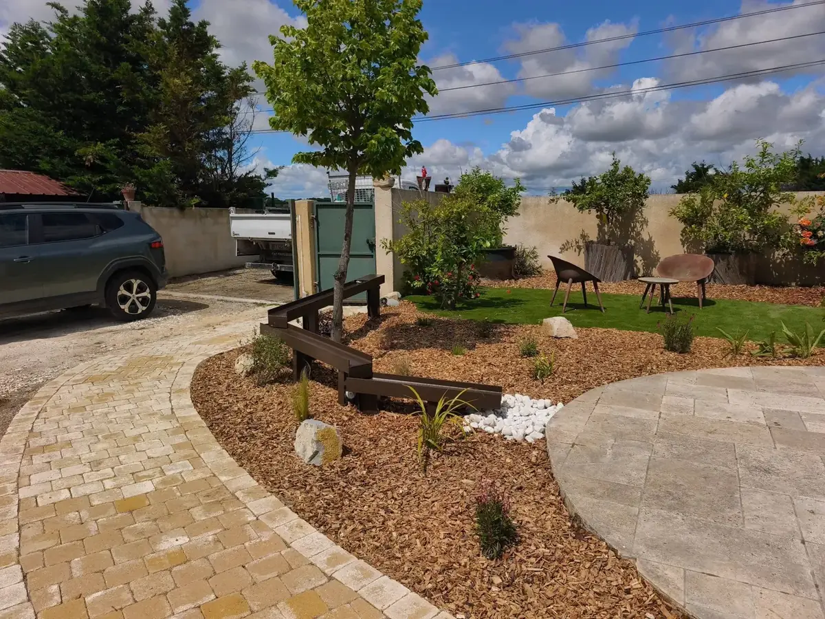 Allée pavée courbe et massifs paillés dans un jardin