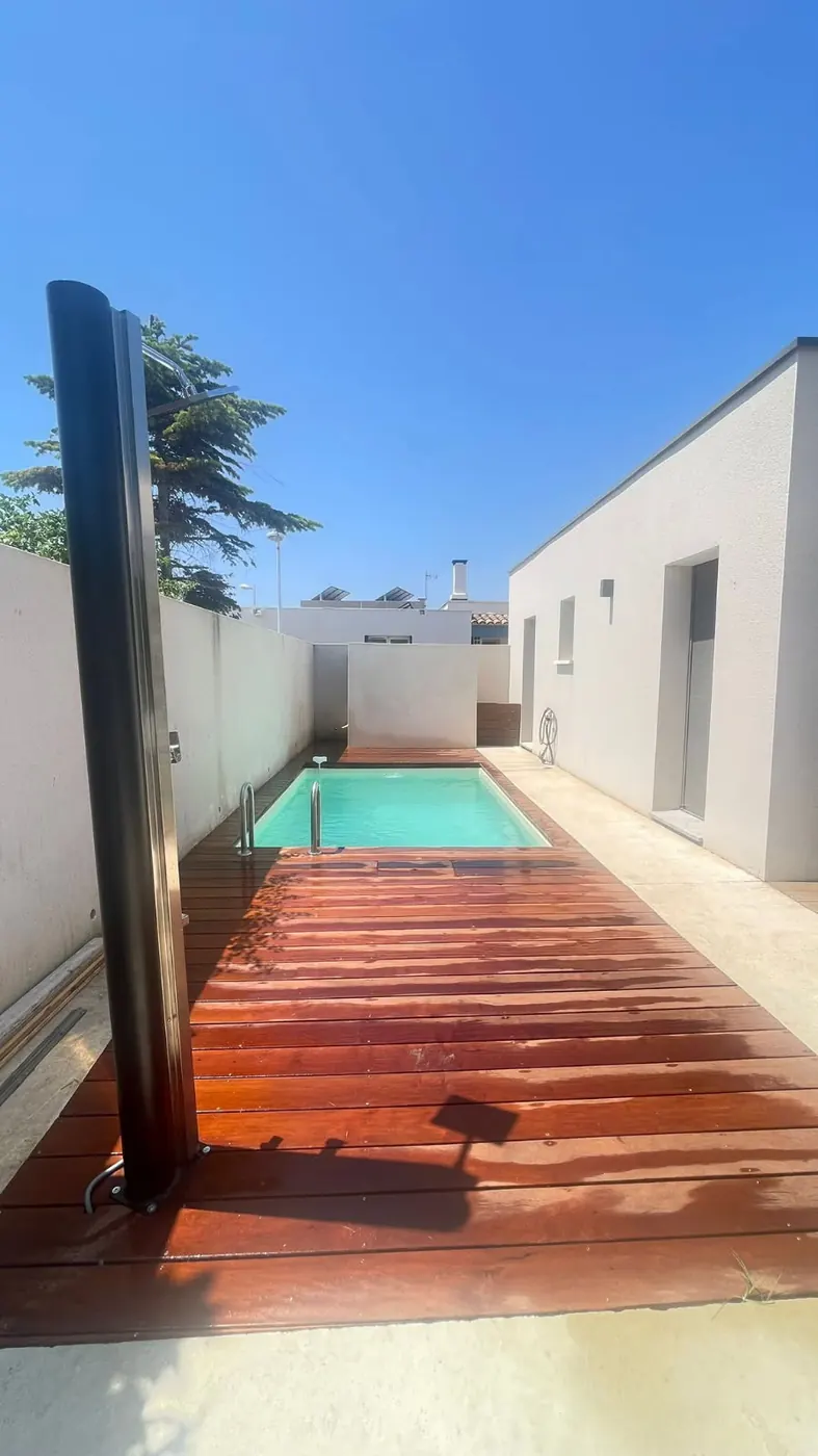 Deck en bois exotique menant à une piscine